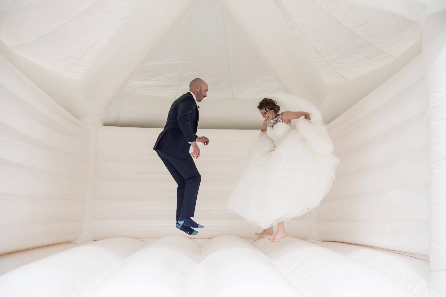 bride and groom jumping on mega white bouncy castle at wedding reception in the North West
